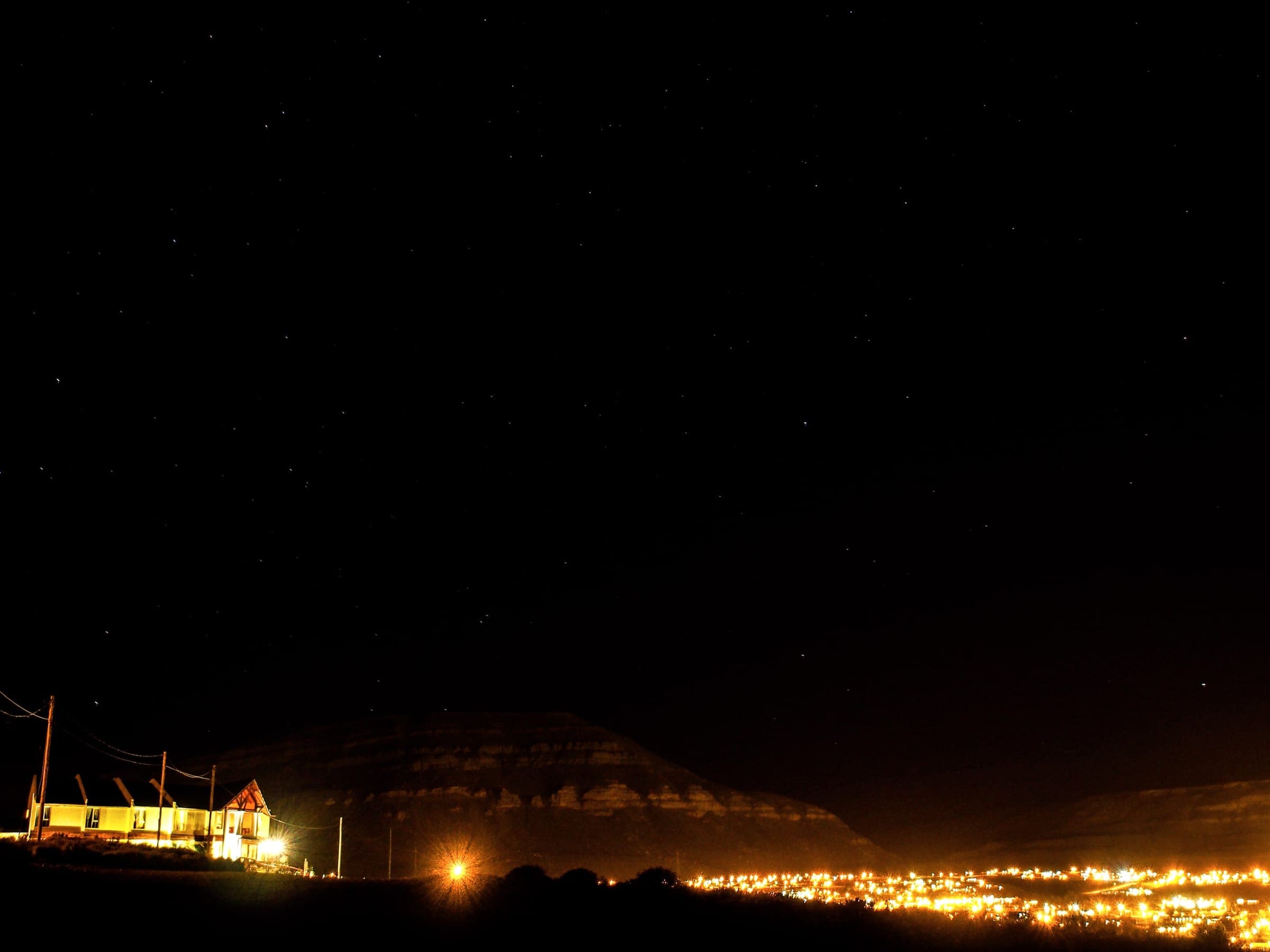 Cielo nocturno sobre el cerro, con las luces de El Calafate abajo