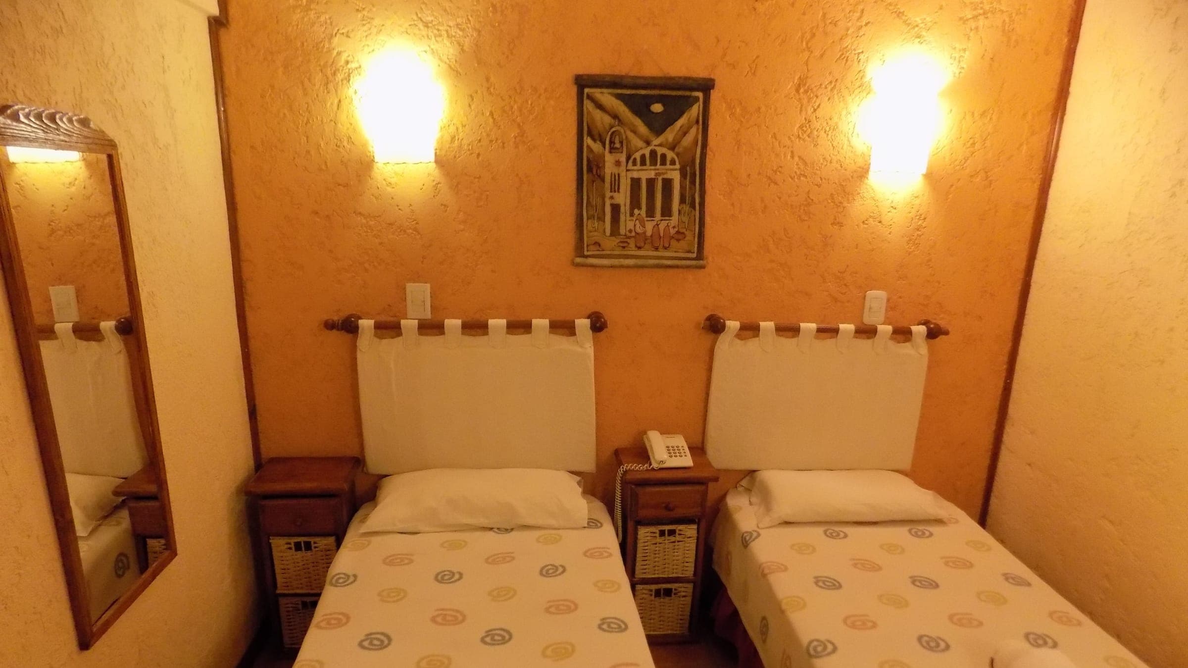 Habitación twin con luz cálida, dos camas y mesas de luz